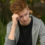 teen boy looking worried rubbing his hand agisnt is temple