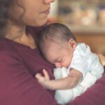 New born baby sleeps in their mothers arms.